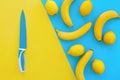 Yellow bananas and lemons on bright blue paper and big knife, tr Royalty Free Stock Photo