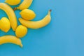 Yellow bananas and lemons on bright blue paper, trendy flat lay. Royalty Free Stock Photo