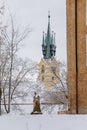 Yellow baroque church of St. James the Elder with gothic clock tower, medieval historical buildings, Main town square under snow