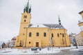 Yellow baroque church of St. James the Elder with gothic clock tower, medieval historical buildings, Main town square under snow