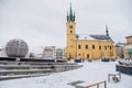 Yellow baroque church of St. James the Elder with gothic clock tower, medieval historical buildings, Main town square under snow