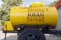 Yellow barrel trailer on black wheels with a drink kvass with the inscription `KVASS` in russian and ornament on its board