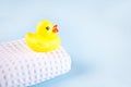 Yellow bath rubber duck on white waffle towel on the blue pink background. Copy space. Royalty Free Stock Photo