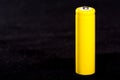 A yellow battery close-up on a dark black blurred background. Electrics. Battery power. Accumulator on the fabric with villi. Royalty Free Stock Photo