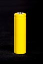 A yellow battery close-up on a dark black blurred background. Electrics. Battery power. Accumulator on the fabric with villi.