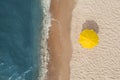 Yellow beach umbrella on sandy coast near sea, top view