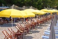 Yellow beach umbrellas and chaise for relax and comfort on sea coast in sunny day. Summer vacations and tourism concept. Paid