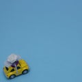 A yellow Beetle with a flower bow on the roof rides on a blue background with copy space. Minimalistic life scene