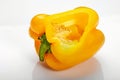 Yellow bell pepper cut sideways, with seeds inside, on a white background