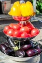 Yellow bell peppers, red tomatoes and purple eggplants on metal three metal bowl outdoors