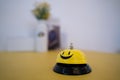 A yellow bell with a smiley face for tapping or pressing is placed on the table on a blurred background Royalty Free Stock Photo