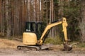 Yellow belt excavator in a pine forest. Hydraulic earthmoving harvester. Rotating operator's cab. Construction industry. Royalty Free Stock Photo