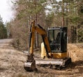 Yellow belt excavator in a pine forest. Hydraulic earthmoving harvester. Rotating operator's cab. Construction industry. Royalty Free Stock Photo