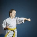 With a yellow belt, sportswoman is beating punch hand on a dark blue background