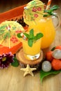 Yellow beverage in glass vessels surrounded by tropical fruits Royalty Free Stock Photo