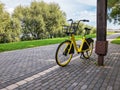 Yellow bicycle parked on paved walkway in city park