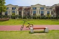 Yellow bicycle on red path in lawn before fenced villas in sunny
