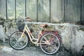 Yellow bicycle is standing in garden, against background of an old brick building. ÃÂ¡oncept of loss, loneliness.