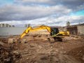 Yellow big excavator at work on construction site in the production of earthworks in bown sand with blue sky with heavy Royalty Free Stock Photo