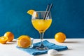 Yellow bird cocktail with rum, orange and lime juice, fruits, blue napkin on white table with dark blue background Royalty Free Stock Photo