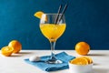 Yellow bird cocktail with rum, orange and lime juice, oranges, blue napkin. White table. Dark blue background. Royalty Free Stock Photo