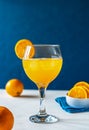 Yellow bird cocktail with rum, orange and lime juice, oranges, blue napkin. White table. Dark blue background. Royalty Free Stock Photo