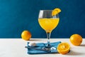 Yellow bird cocktail with rum, orange and lime juice, oranges, blue napkin on white table with dark blue background Royalty Free Stock Photo