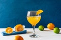 Yellow bird cocktail with rum, orange and lime juice, oranges and limes, blue napkin. White table. Dark blue background Royalty Free Stock Photo