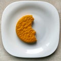 Yellow biscuits on a plate, bitten biscuits on a white plate