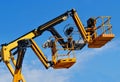 Yellow and black aerial platform baskets against blue sky. Royalty Free Stock Photo