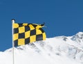 Yellow and black avalanche risk warning flag flying in the mount Royalty Free Stock Photo