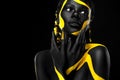 Yellow and black body paint. Woman with face art. Young girl with colorful bodypaint. An amazing afro american model