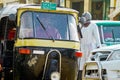 Yellow and black painted tuctuc with smiling driver in the traffic jumble of the capital city Royalty Free Stock Photo