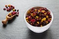 Yellow and black raisins and dried red cranberry in white bowl, wooden scoop on stone background Royalty Free Stock Photo