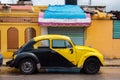 Yellow and black retro car Volkswagen Beetle parked on the old street