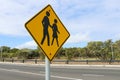 Yellow and black sign indicating to take care when crossing a busy road Royalty Free Stock Photo