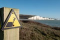 Sign warning of the danger of erosion at the cliff edge overlooking Seven Sisters at Seaford in East Sussex, south coast of UK Royalty Free Stock Photo