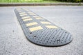 Yellow and black speed bumps on the asphalt road. Obstacle in the path of vehicles to reduce the speed and safety of