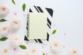 yellow and black and white notebooks, pink plastic hearts and many pink flowers of chrysanthemums and green leaves on a white tabl Royalty Free Stock Photo