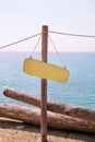 Yellow blank billboard on sandy beach. Just add your text. Beach sign by sea. Blank rustic wooden sign on beach. Royalty Free Stock Photo