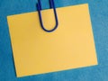 yellow blank note pinned to a blue notice board with a paper clip Royalty Free Stock Photo