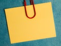 yellow blank note pinned to a blue notice board with a paper clip Royalty Free Stock Photo