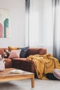 Yellow blanket on brown corner sofa in trendy living room interior Royalty Free Stock Photo