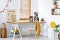 Yellow blanket on chair at wooden desk with lamp and colorful yarns in modern interior. Real photo Royalty Free Stock Photo