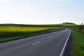 yellow blooming fields at the roadside with an approaching truck in the curves Royalty Free Stock Photo