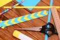 Yellow and blue bookmark from folded paper. Scissors, glue stick, colored paper sheets, ruler, pencil on a desk. Simple paper art Royalty Free Stock Photo