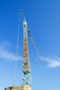 Yellow blue construction tower crane against the clear blue sky on a sunny winter day. Modern construction machinery Royalty Free Stock Photo