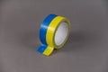 Yellow and blue duct tape. Reel of colored duct tape against the gray background. Selective focus. No people