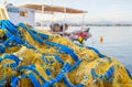 A yellow-and-blue fishing net is piled near a fishing boat Royalty Free Stock Photo