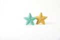 Yellow and blue-green knitted five-pointed star shaped pillows on white background - two pieces.